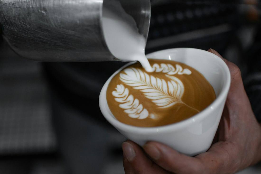 Barista sirviendo arte latte en una taza